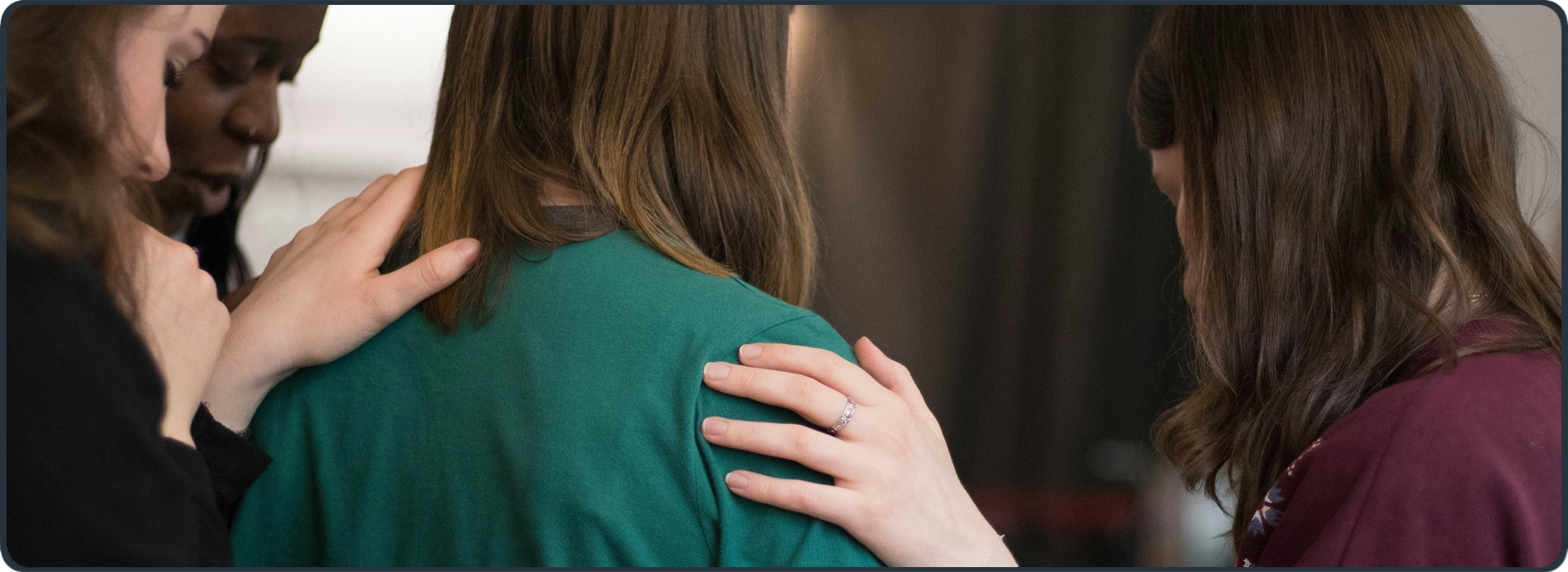 Menschen legen betend die Hände auf eine Frau – Symbol für geistliche und finanzielle Unterstützung aus der Gemeinde