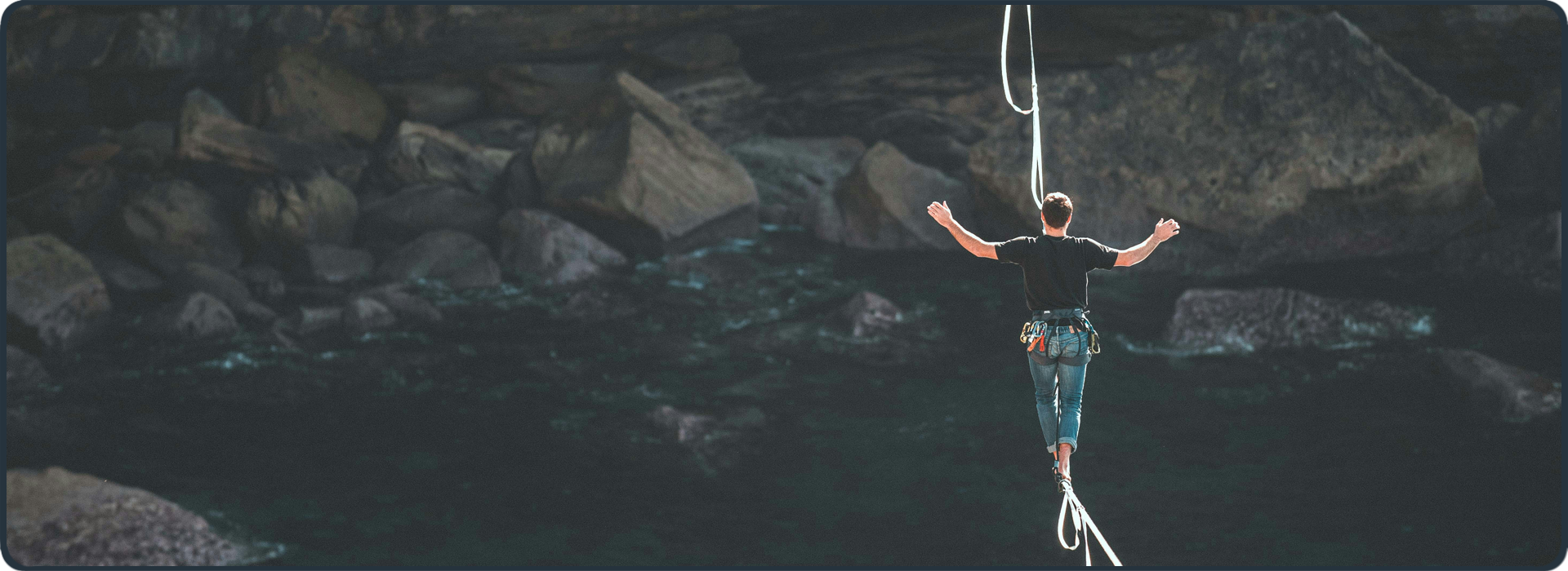 Mann balanciert gesichert auf Slackline über Felsen – Symbol für Herausforderungen und Balance im geistlichen Dienst
